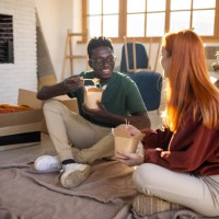 young couple eating noodles in their new apartment - junk food stock pictures, royalty-free photos & images