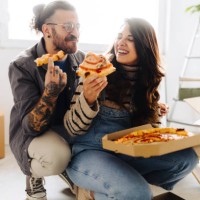 young couple eating pizza in new home - junk food stock pictures, royalty-free photos & images
