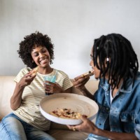 young couple eating pizza together at home - junk food stock pictures, royalty-free photos & images