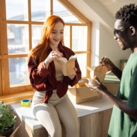 young couple eating take out noodles in their new apartment - junk food stock pictures, royalty-free photos & images