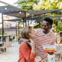 young couple is eating fast food on the street - junk food stock pictures, royalty-free photos & images