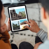 young couple looking at photo album on digital tablet - travel stock-fotos und bilder