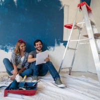 young couple looking very happy painting their house - home decoration stock pictures, royalty-free photos & images