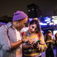 young couple (or friends) using mobile phone at festival by the night - including a transgender person - fashion stock pictures, royalty-free photos & images