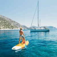 young couple paddling on stand up paddleboards against the yacht in the sea. - travel photos et images de collection