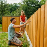 young couple painting a picket fence - home decoration stock pictures, royalty-free photos & images