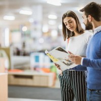 young couple reading catalog in furniture store. - home decoration stock pictures, royalty-free photos & images