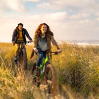young couple ride fat bikes on coastal trail - travel stock pictures, royalty-free photos & images