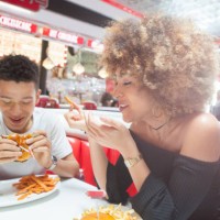 young couple, sitting in diner, eating meal - junk food stock pictures, royalty-free photos & images