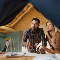 young couple talking about plans with an architect at construction site. - home decoration stock pictures, royalty-free photos & images
