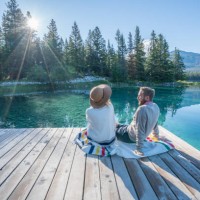 young couple watching sunrise on lake pier - travel stock pictures, royalty-free photos & images