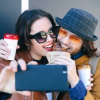 young couple with croissant and coffee to go taking selfie with smartphone - junk food stock pictures, royalty-free photos & images