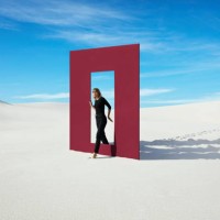 young fashion model walking through red door frame at desert against sky - fashion stock pictures, royalty-free photos & images