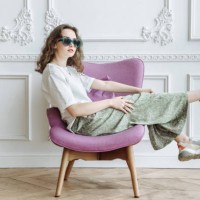 young fashionable woman model posing sitting on an armchair in the studio in trendy modern clothes from the new collection catalog - home decoration stock pictures, royalty-free photos & images