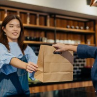 young female barista giving take out food to customer in cafe - junk food stock pictures, royalty-free photos & images