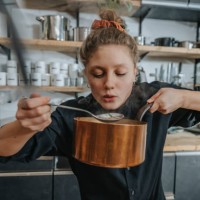 young female chef tasting broth soup while standing in kitchen - food stock pictures, royalty-free photos & images