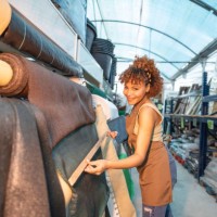 young female worker measuring and looking at blackout tarpaulins for fences, concealment fabric for home perimeter - garden decoration stock pictures, royalty-free photos & images