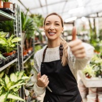 young florist working in greenhouse holding thumbs up - garden decoration stock pictures, royalty-free photos & images