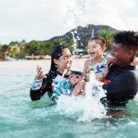 young girl and adult friends splash in the ocean together - travel stock pictures, royalty-free photos & images