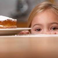 young girl in kitchen peeking over counter with a cake on it - junk food stock pictures, royalty-free photos & images