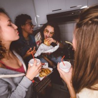 young girls having fun eating fast food at house party - junk food stock pictures, royalty-free photos & images
