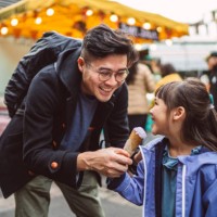 young handsome dad feeding ice cream to her lovely daughter in front of ice cream stall in food market - junk food stock pictures, royalty-free photos & images