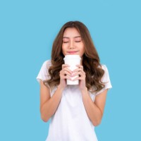 young happy asian woman feeling happiness wearing white shirt standing isolated over cyan background, holding takeaway coffee cup - junk food stock pictures, royalty-free photos & images