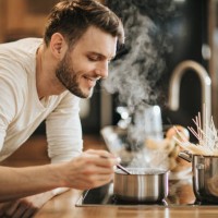 young happy bachelor enjoying in the smell of his cooking. - food stock pictures, royalty-free photos & images