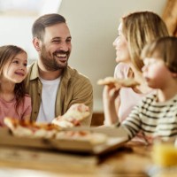 young happy family talking while eating pizza for lunch at home. - junk food stock pictures, royalty-free photos & images