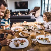 young happy family talking while having lunch at dining table. - food stock pictures, royalty-free photos & images