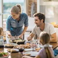 young happy woman serving lunch to her family at dining table. - food stock pictures, royalty-free photos & images