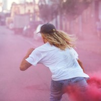 young male skateboarder wearing white t-shirt carrying a pink flare as he skates away down the street - fashion stock pictures, royalty-free photos & images