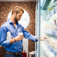 young man choosing food from cooling shelf in a coffee shop - junk food stock pictures, royalty-free photos & images