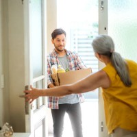 young man delivering groceries to elderly woman at home - food stock pictures, royalty-free photos & images