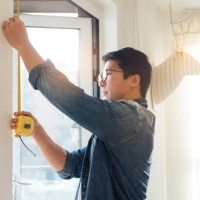 young man doing diy using measuring tape at home - home decoration stock pictures, royalty-free photos & images