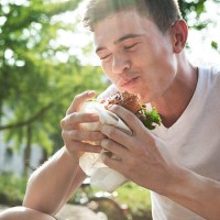 young man eating hamburger - food stock pictures, royalty-free photos & images