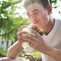 young man eating hamburger - junk food stock pictures, royalty-free photos & images
