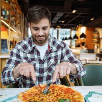 young man eating pizza and enjoying italian food in restaurant - junk food stock pictures, royalty-free photos & images