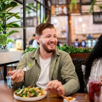 young man eating with his friends on a restaurant - food stock pictures, royalty-free photos & images