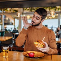 young man enjoying a delicious burger - food stock pictures, royalty-free photos & images