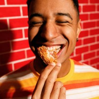 young man enjoying crispy chicken - junk food stock pictures, royalty-free photos & images