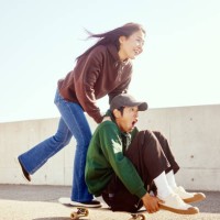 young man enjoys pushing his friend sitting on a skateboard from behind with his hand. - fashion stock pictures, royalty-free photos & images