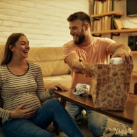 young man having dinner on the floor with his pregnant wife - junk food stock pictures, royalty-free photos & images