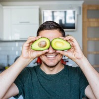 young man having fun with avocado at the kitchen - food stock pictures, royalty-free photos & images