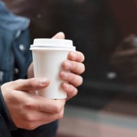 young man holding a takeaway coffee outdoors - junk food stock pictures, royalty-free photos & images