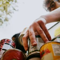 young man holding canned food in box - food stock pictures, royalty-free photos & images