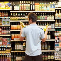 young man in supermarket comparing bottles of oil, rear view, close-up - food stock pictures, royalty-free photos & images