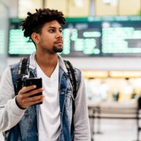 young man inside the airport holding a mobile phone. - travel photos et images de collection