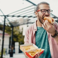 young man is eating hot dog - junk food stock pictures, royalty-free photos & images