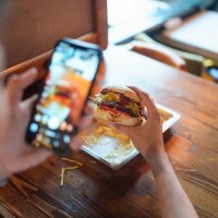 young man is taking a photo of his burger with his phone - food stock pictures, royalty-free photos & images